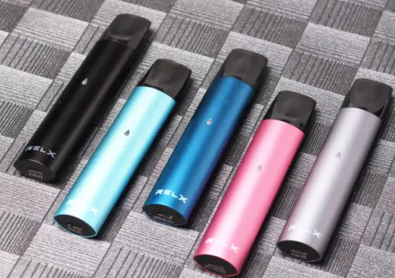 Five RELX-branded pod devices standing in a row on a fabric surface